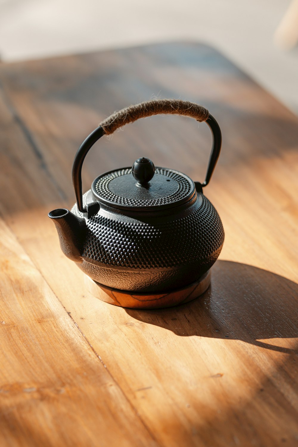a black teapot sitting on top of a wooden table