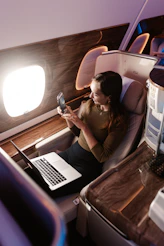 a woman sitting in an airplane looking at her cell phone