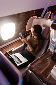 a woman sitting in an airplane looking at her cell phone