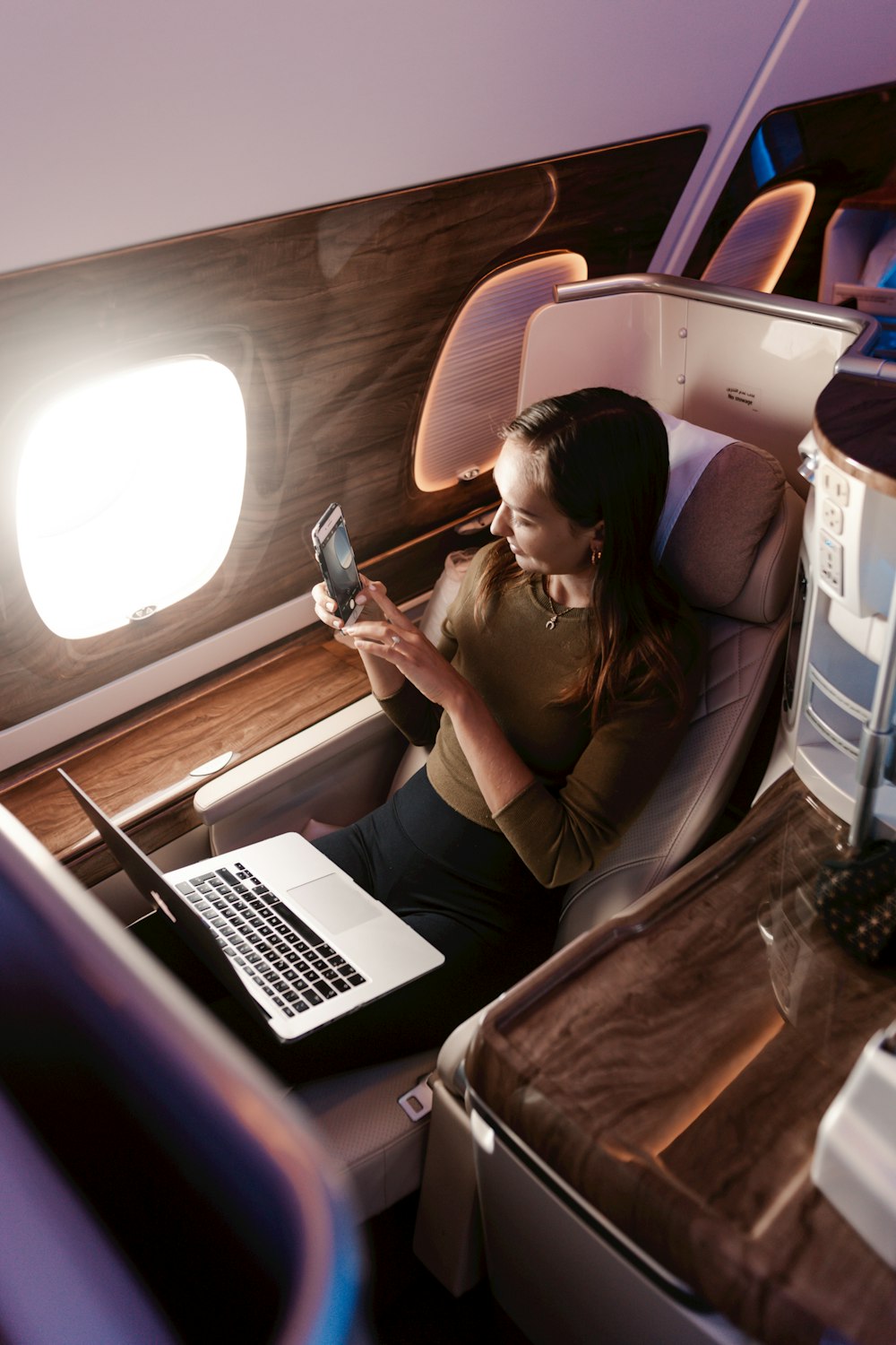 uma mulher sentada em um avião olhando para seu telefone celular
