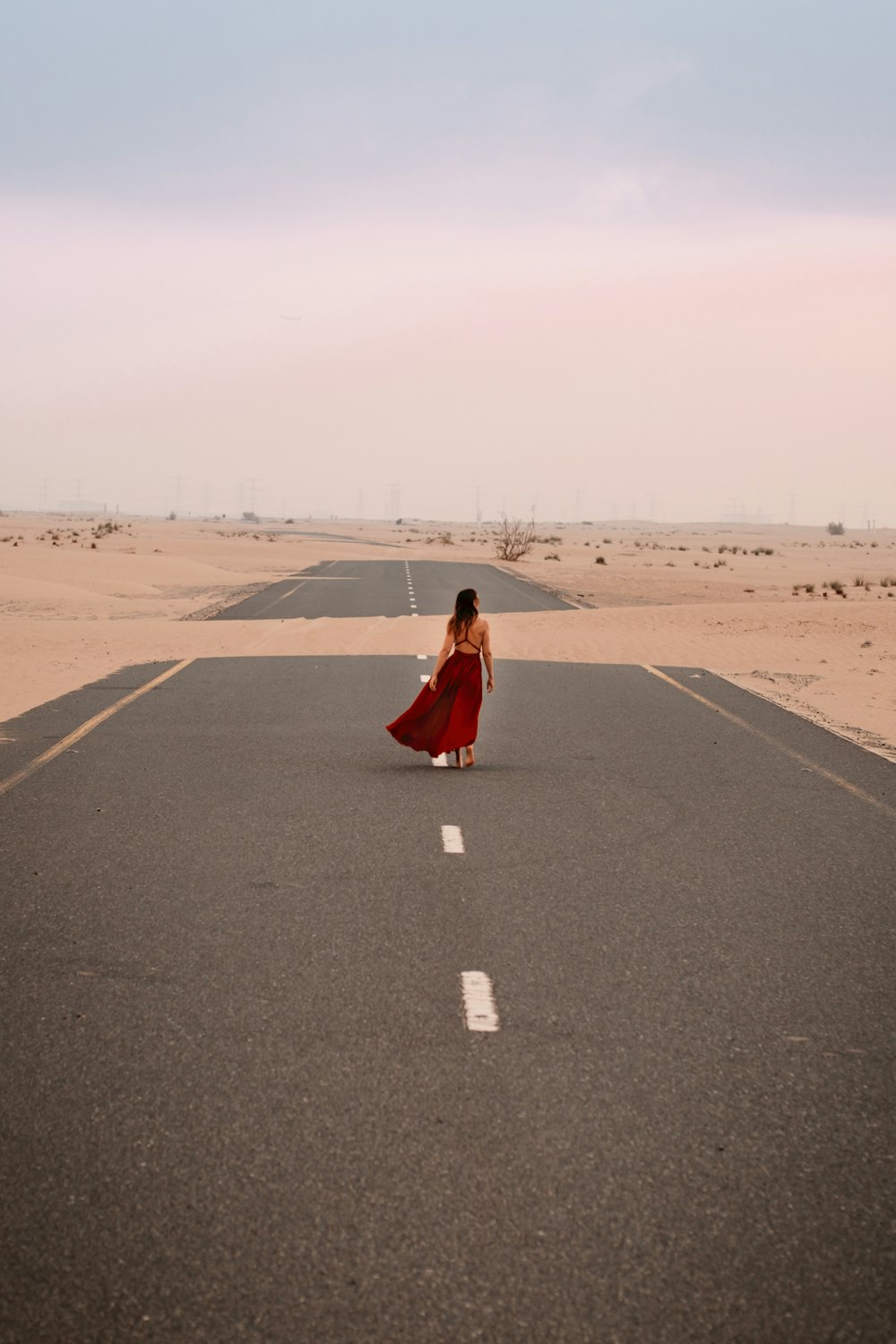 a woman in a red dress is walking down the road