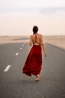 a woman in a red dress is walking down the road