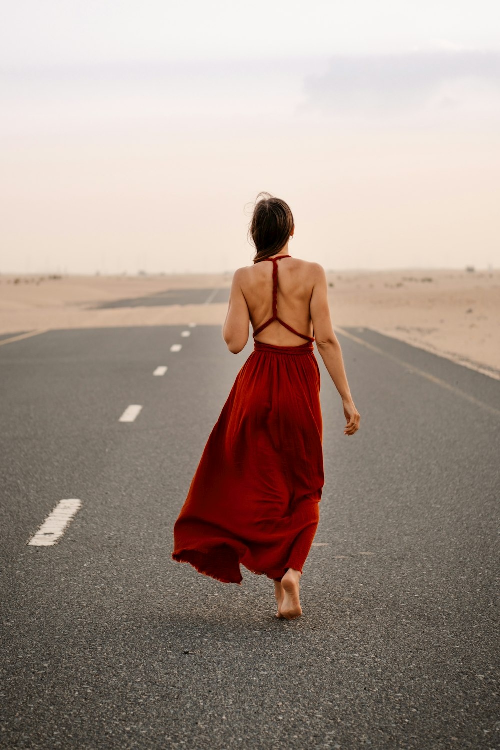 a woman in a red dress is walking down the road