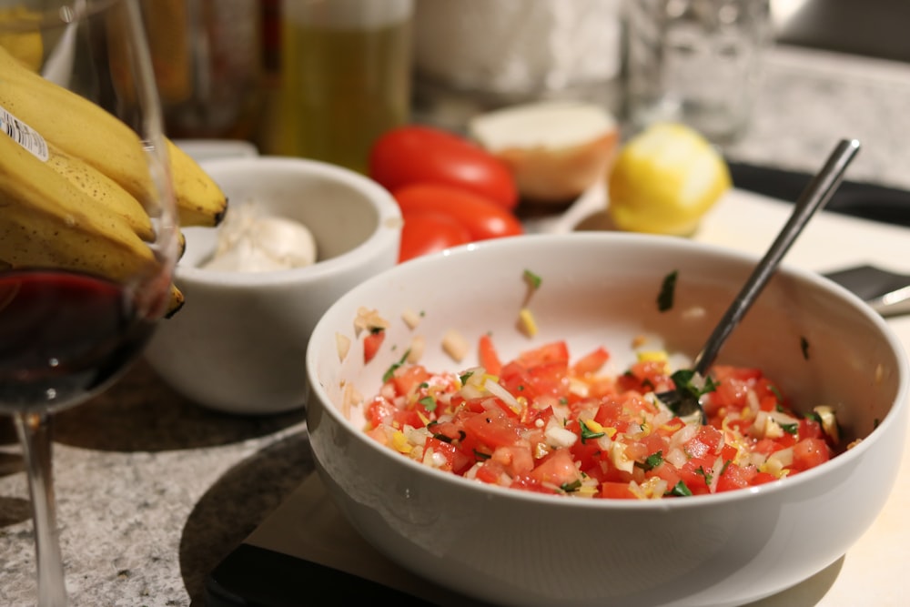 a bowl of food with a glass of wine next to it