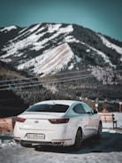 A scenic taxi parked by the roadside with snow-capped mountains in the background.