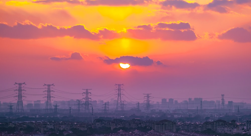 the sun is setting over a city with power lines