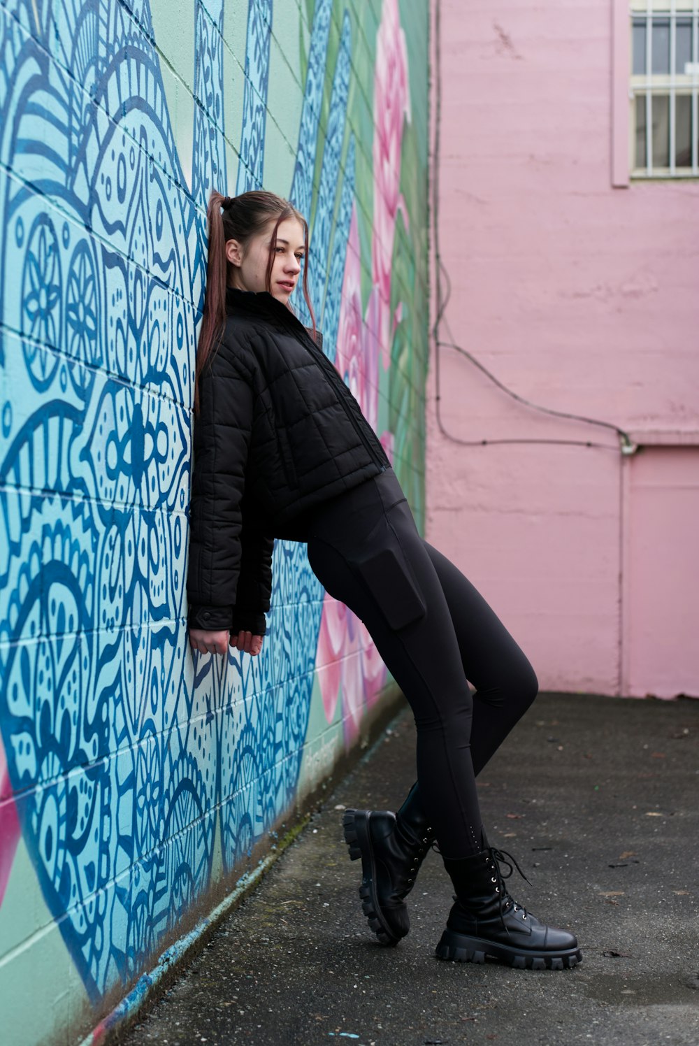 a woman leaning against a wall in front of a painted wall