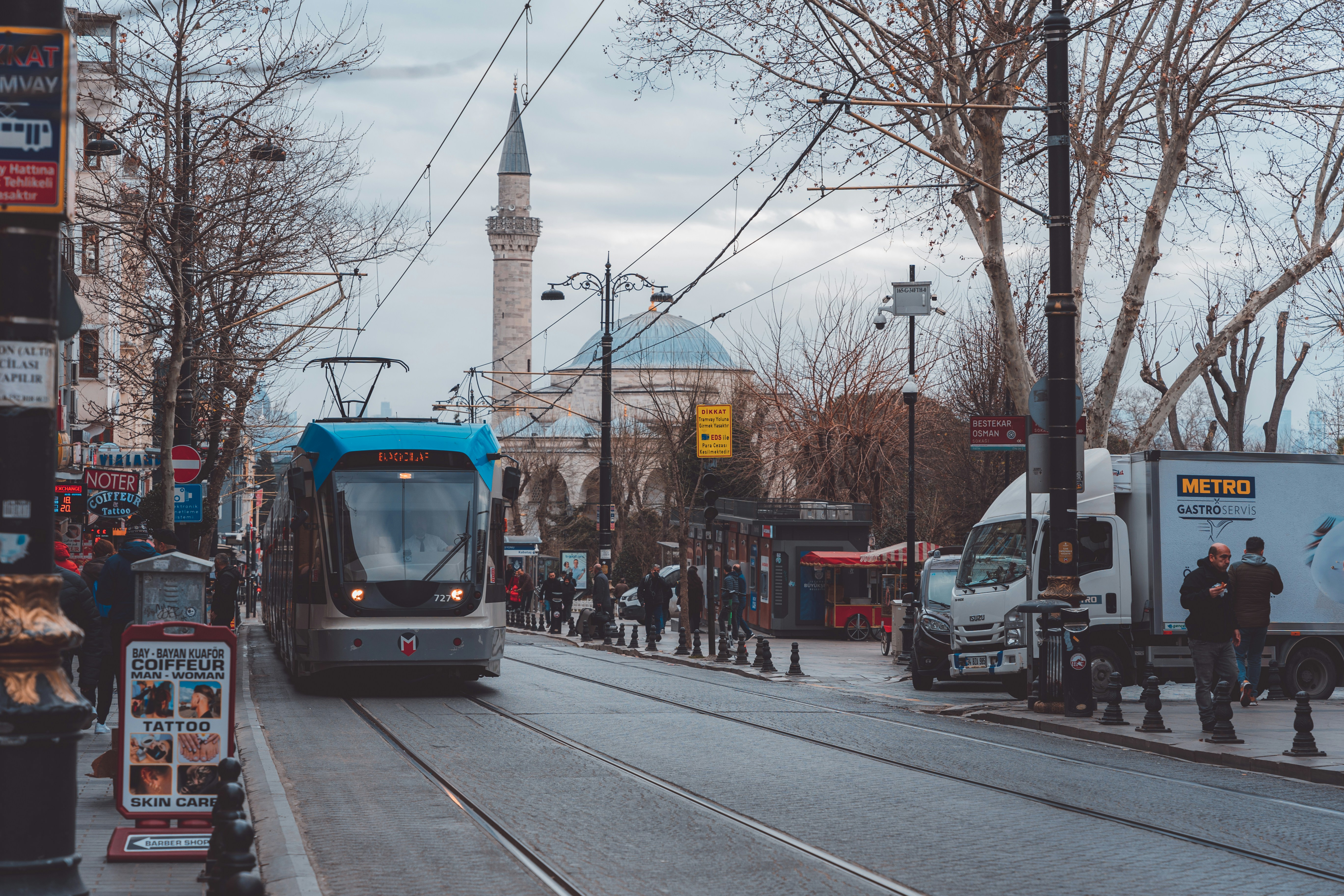 a blue and white train traveling down a street next to tall buildings