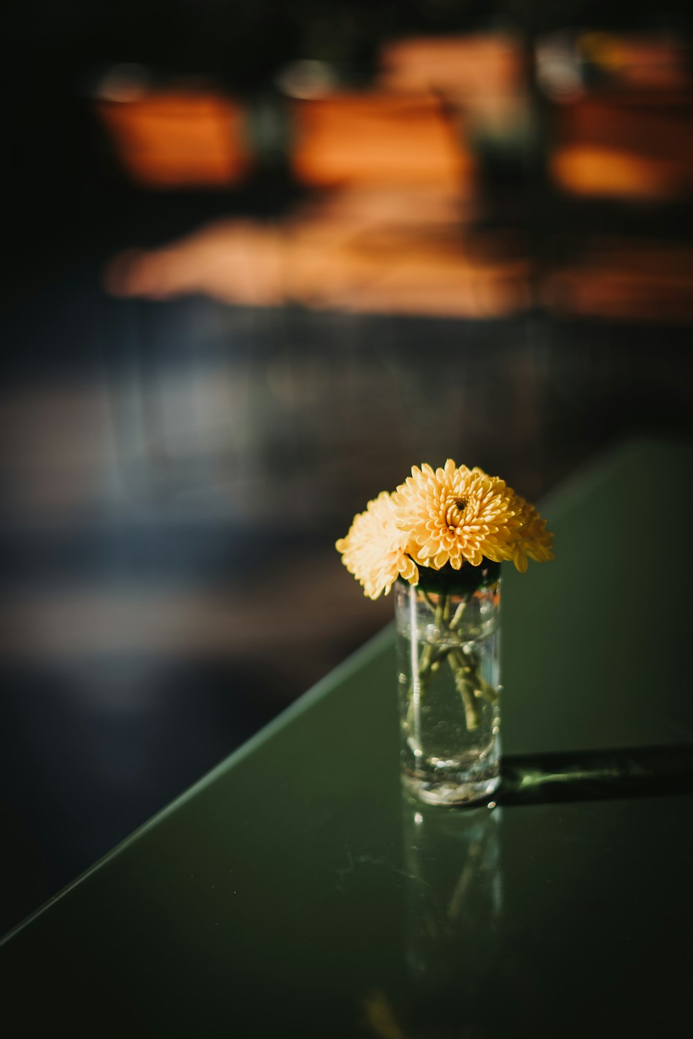 a small glass vase with a yellow flower in it