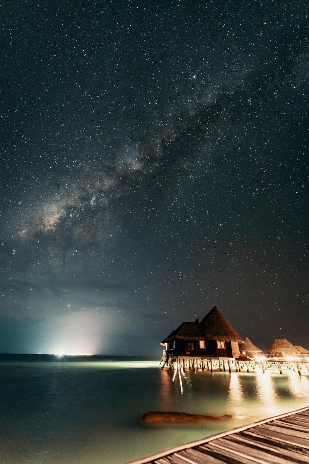 o céu noturno sobre a água e um cais de madeira