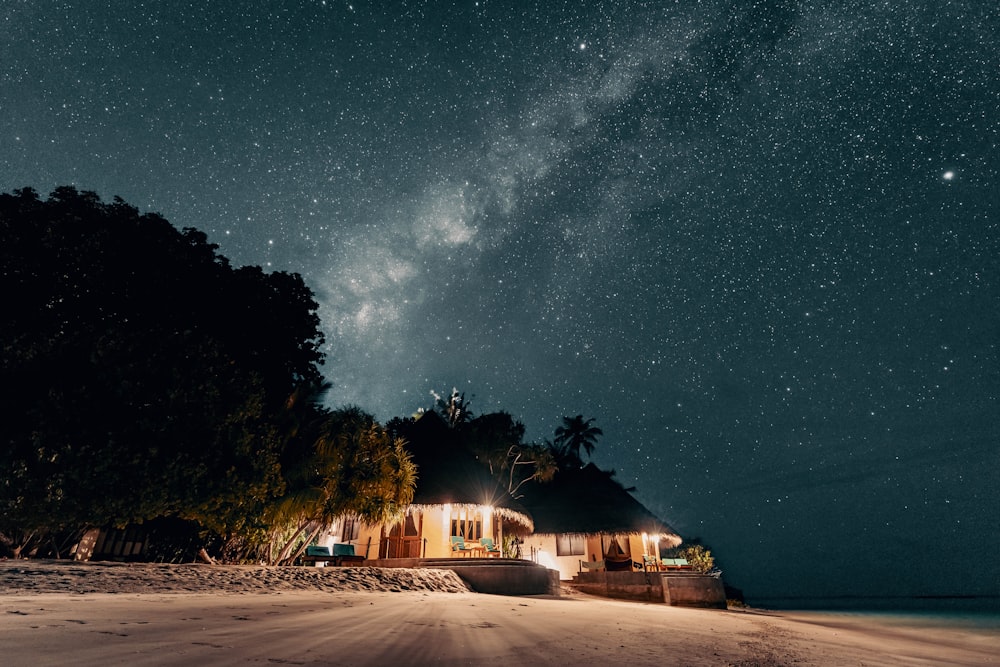 uma casa em uma praia sob um céu noturno