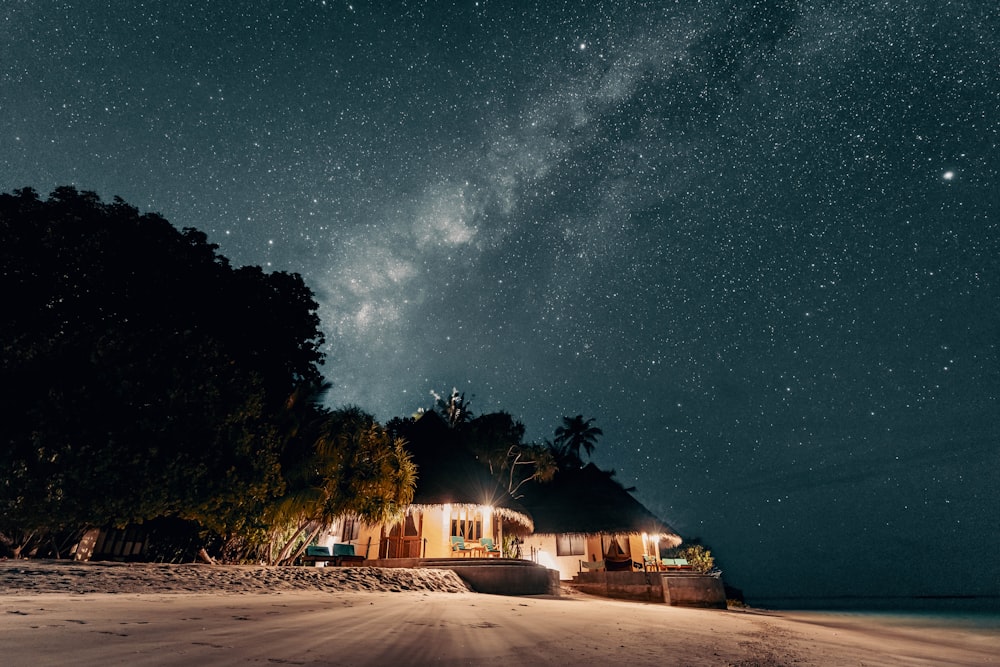 a house on a beach under a night sky
