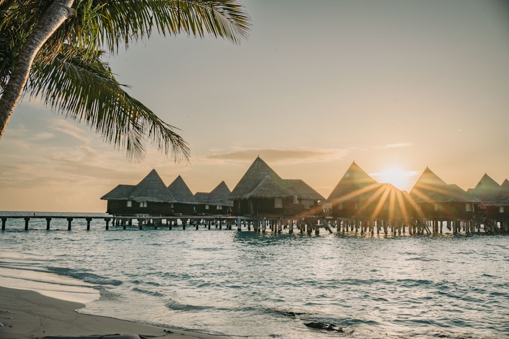 the sun is setting over the water and a pier