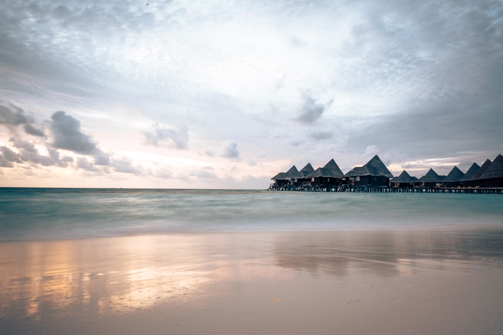 a sandy beach with a row of huts in the distance