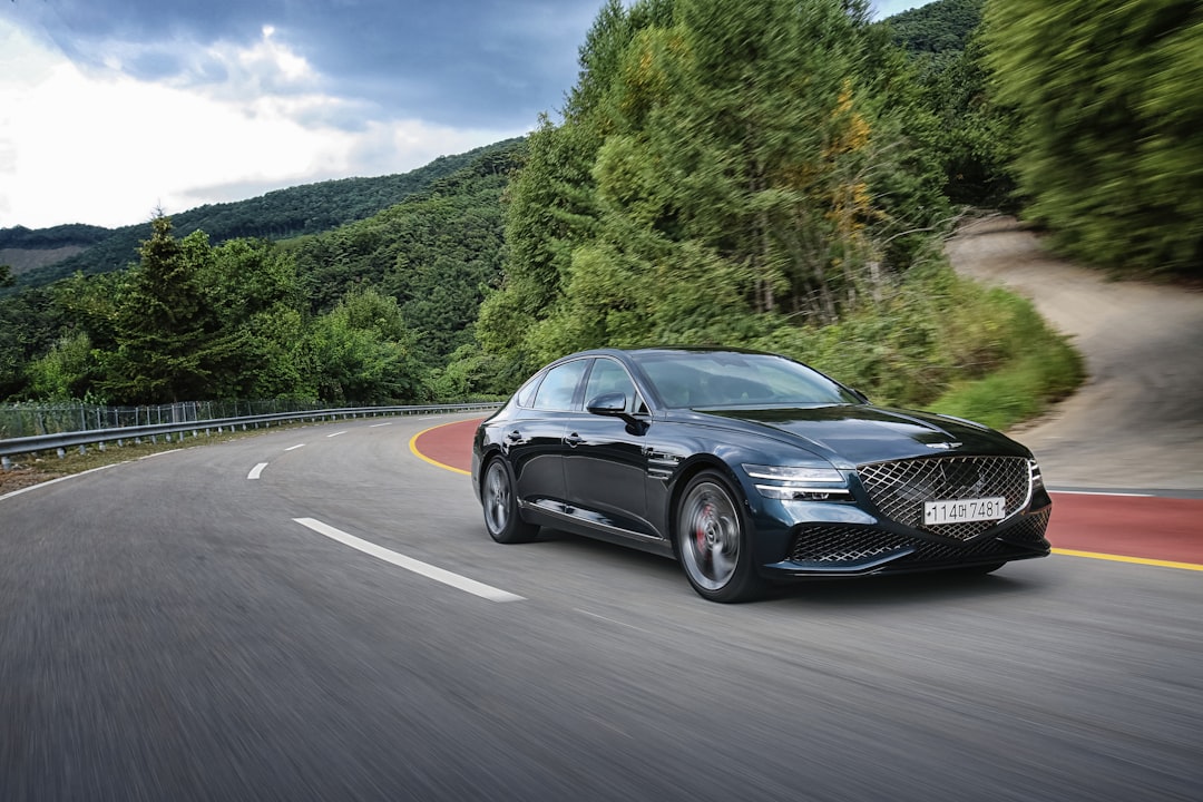 a black car driving down a winding road, The Genesis G80 Sport driving up a mountain road