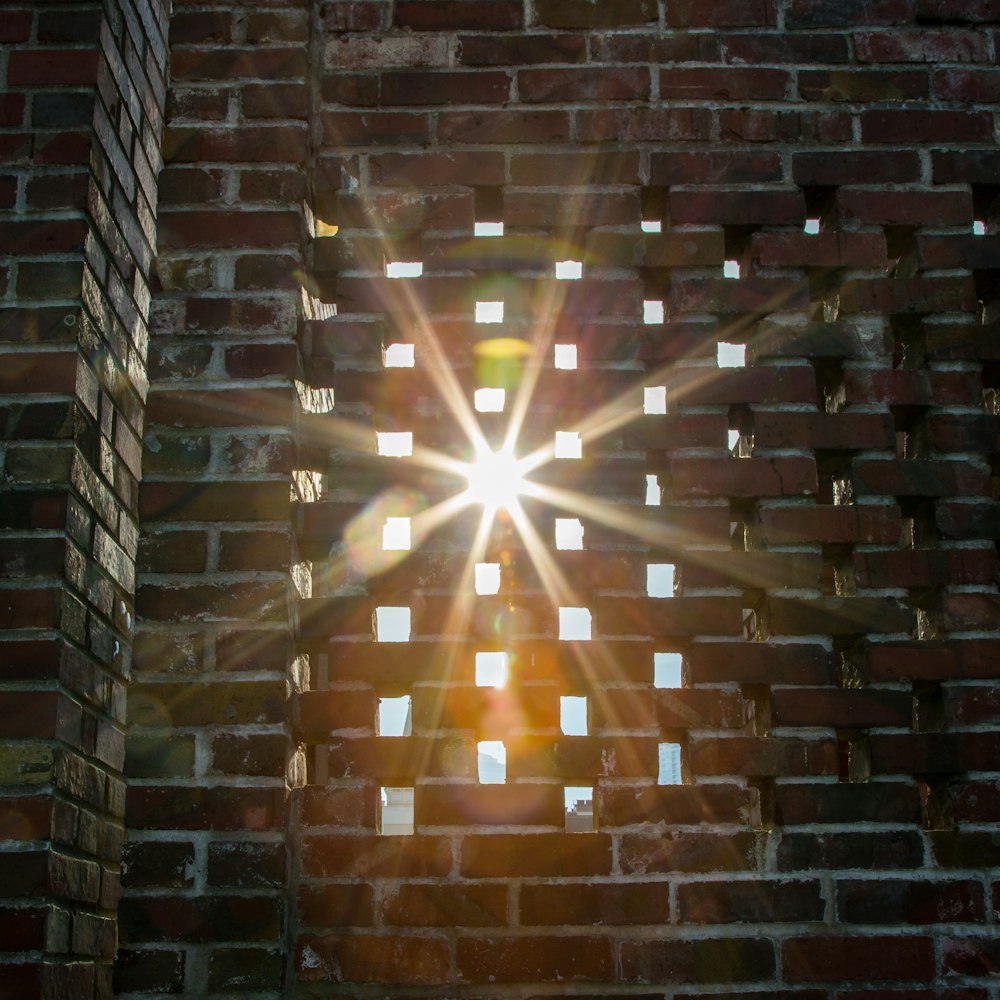 the sun shining through a hole in a brick wall
