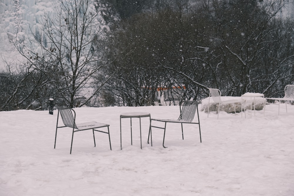 a couple of chairs sitting on top of a snow covered field