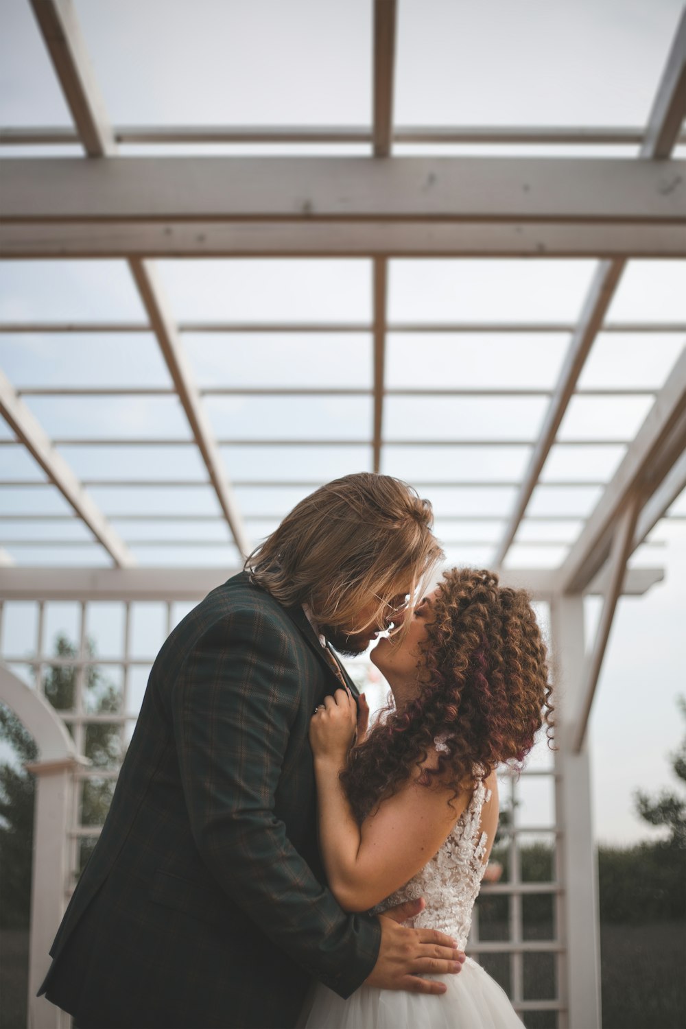 a bride and groom kissing under a pergolan