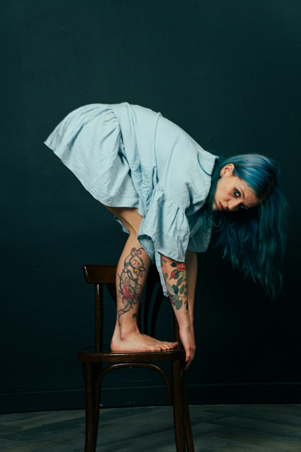 a woman with blue hair leaning on a chair