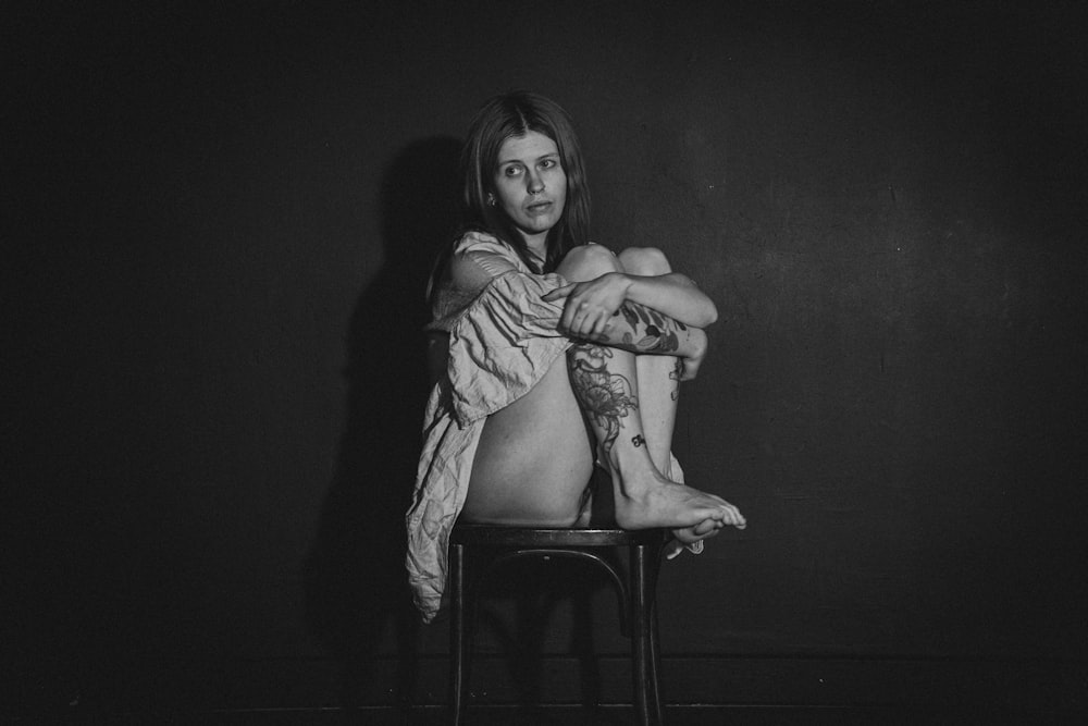 a black and white photo of a woman sitting on a chair