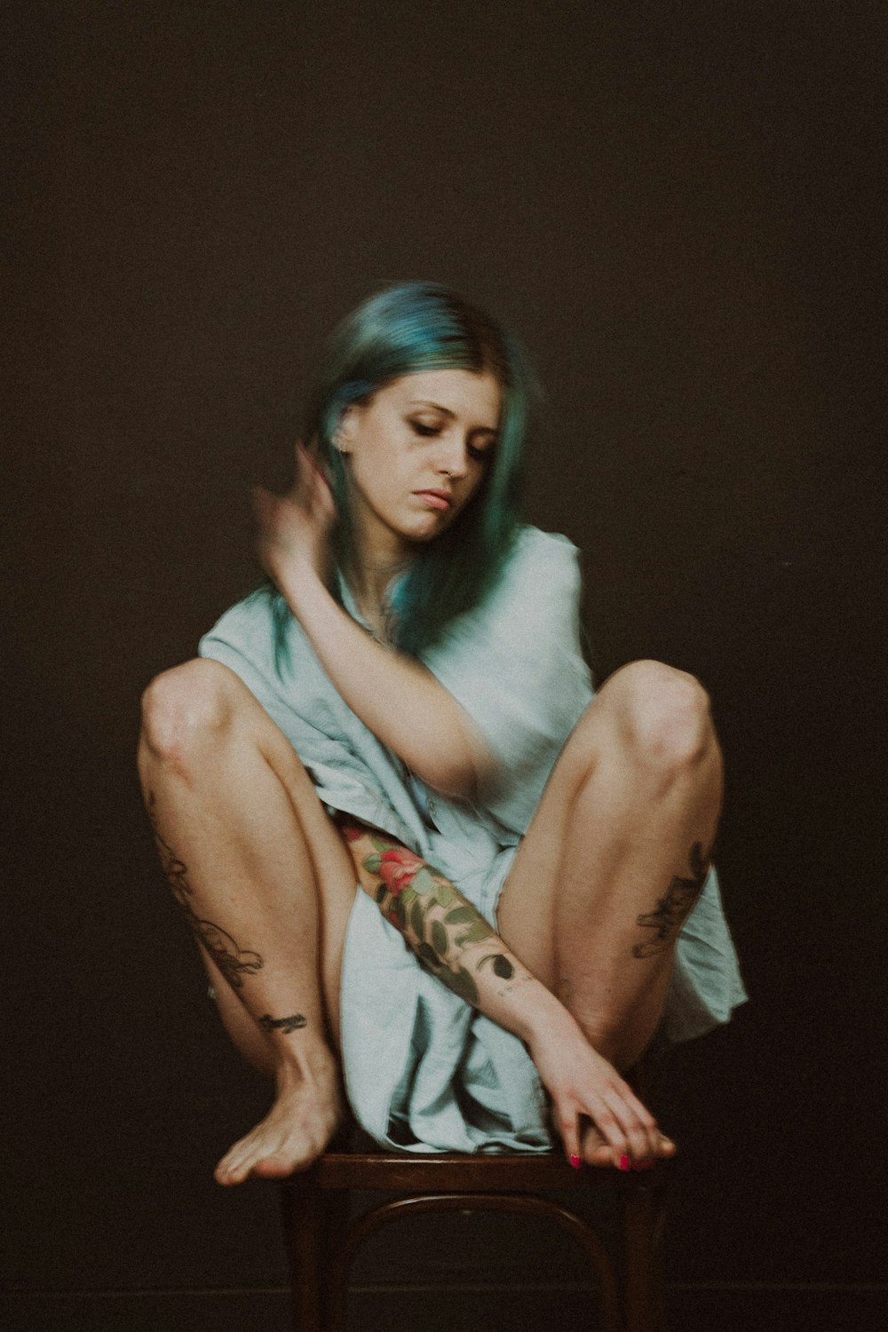 a woman with tattoos sitting on a stool