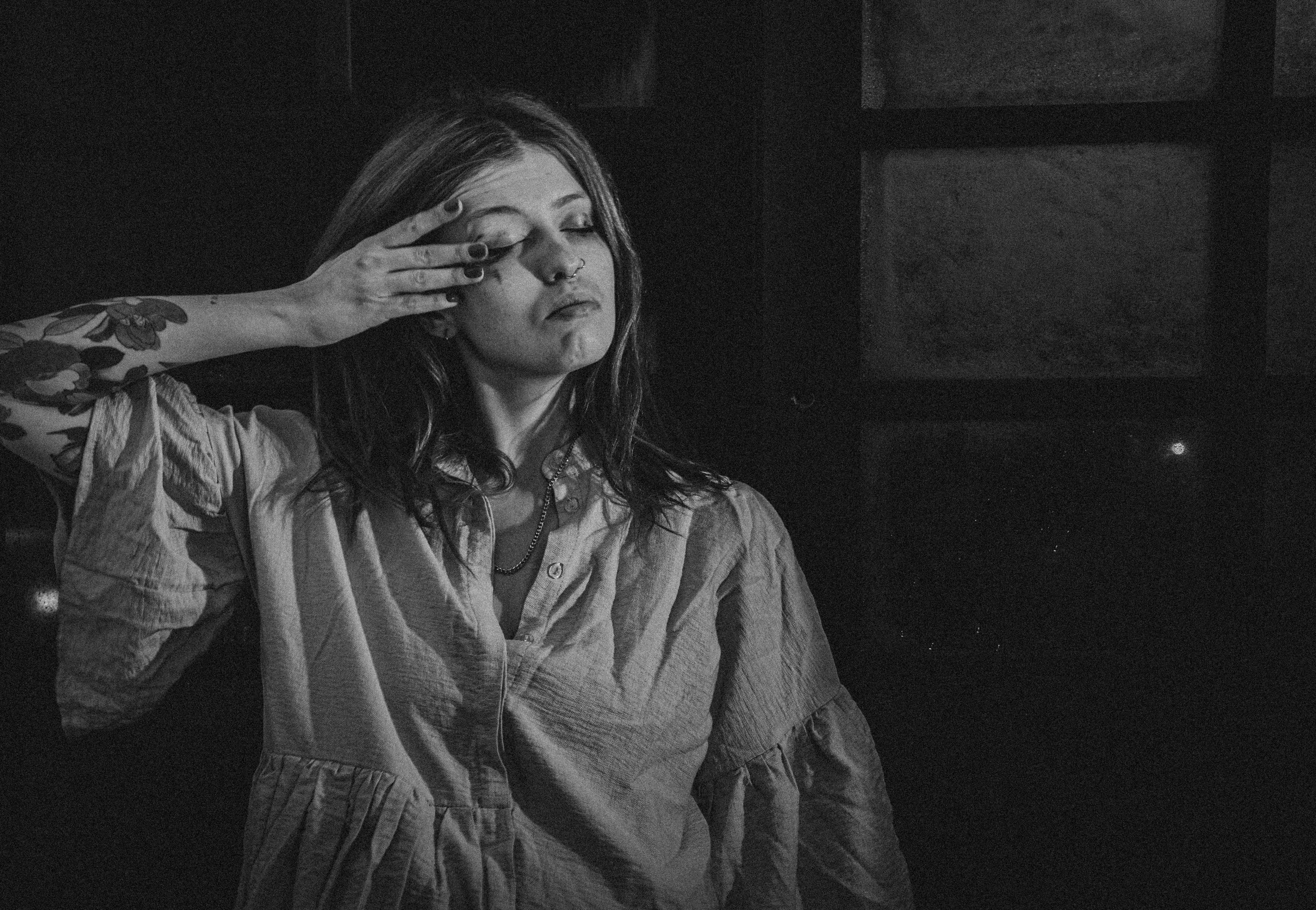 a black and white photo of a woman covering her eyes