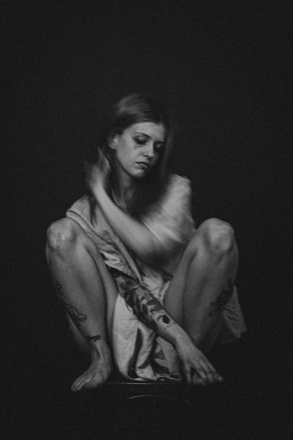 a black and white photo of a woman sitting on the ground