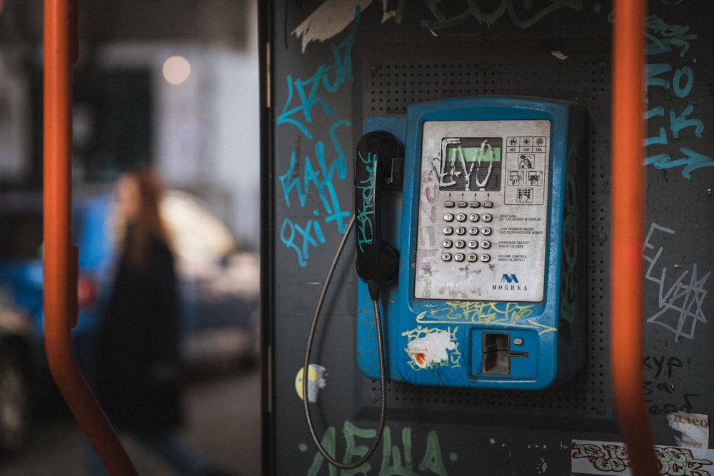 a blue phone sitting on top of a wall covered in graffiti