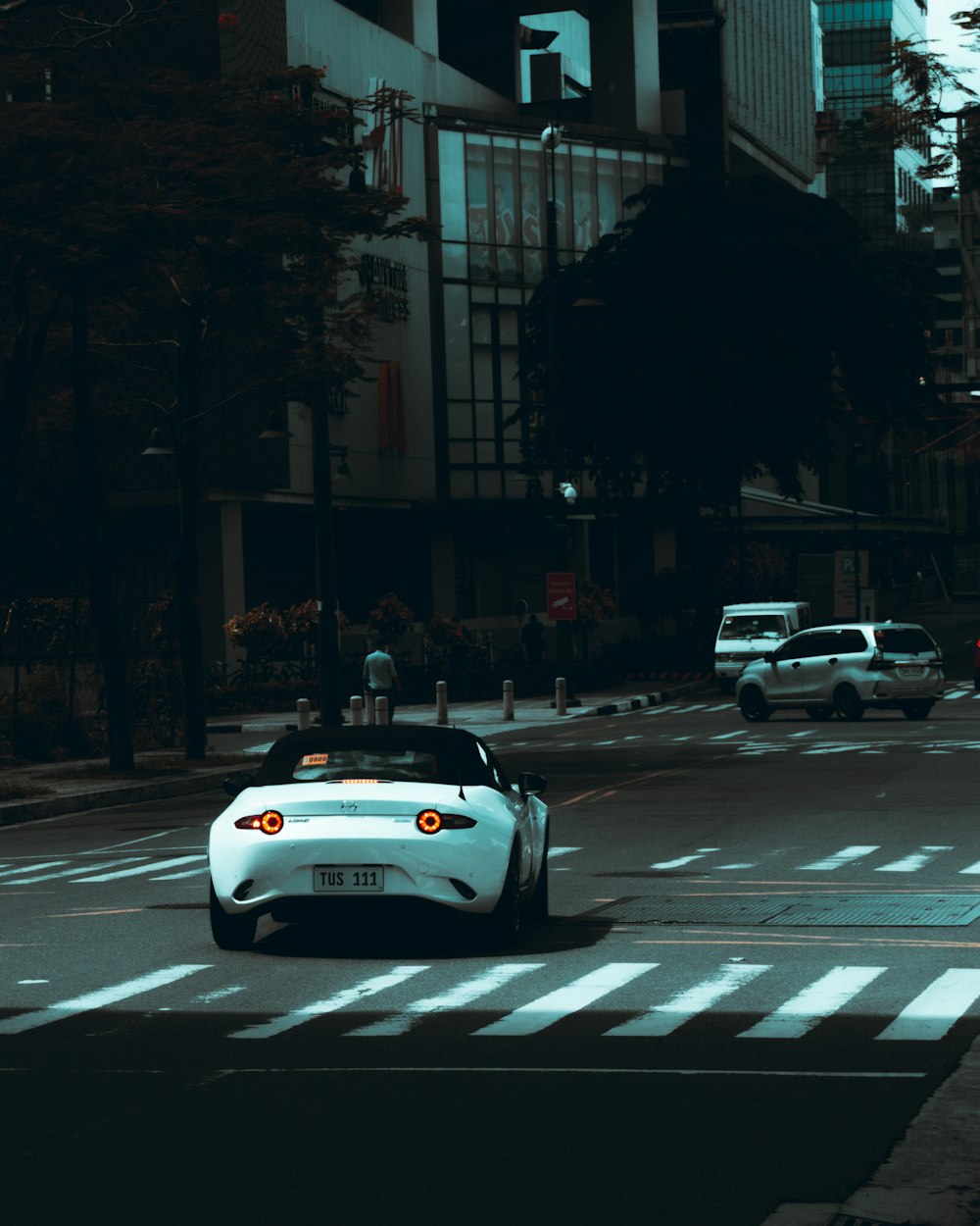 a white sports car driving down a city street