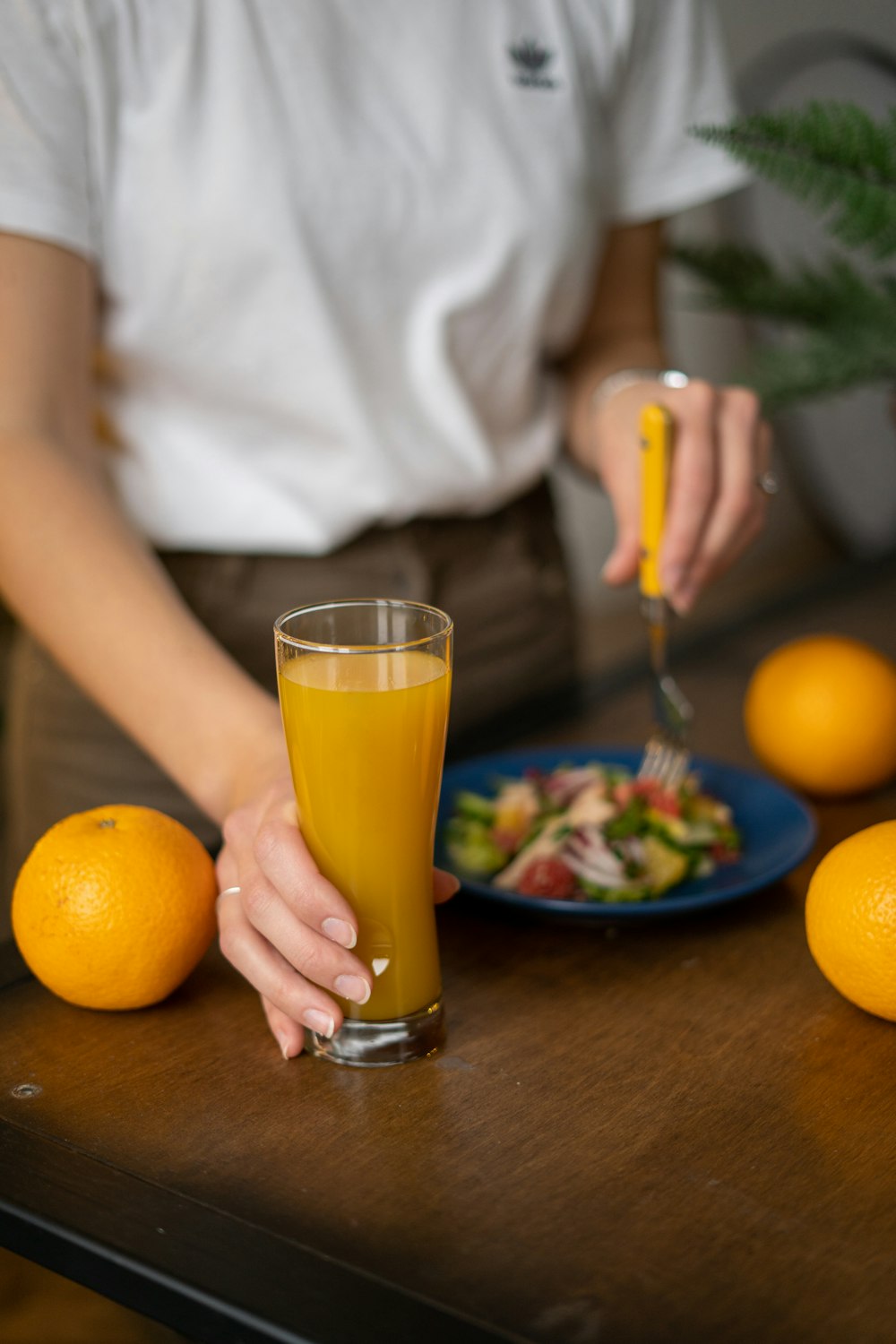 a woman is holding a glass of orange juice