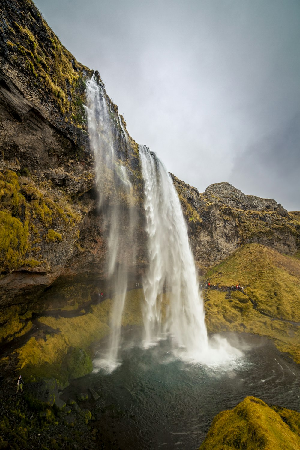 a large waterfall with green moss growing on the side of it