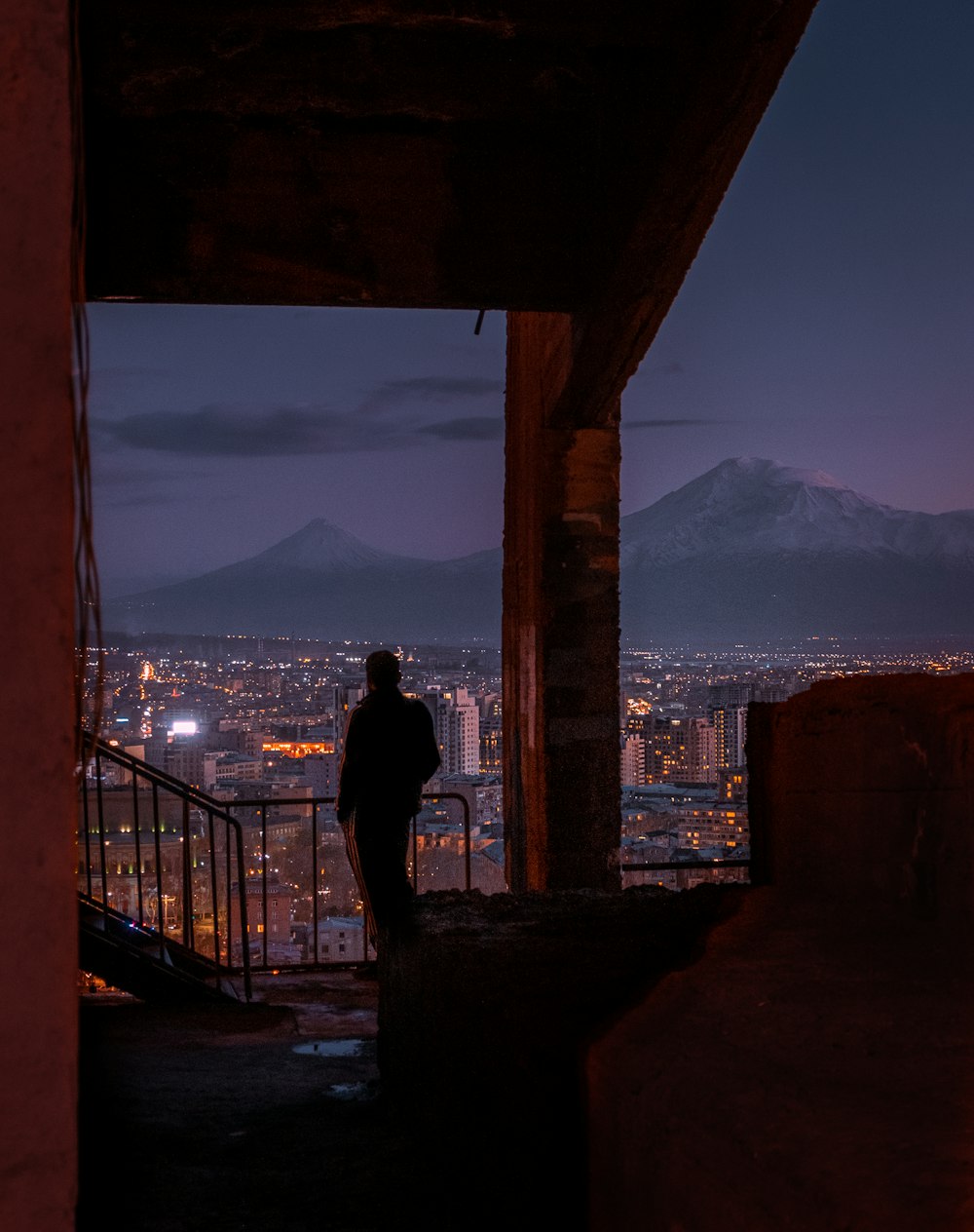 Una persona parada en un balcón con vistas a una ciudad por la noche