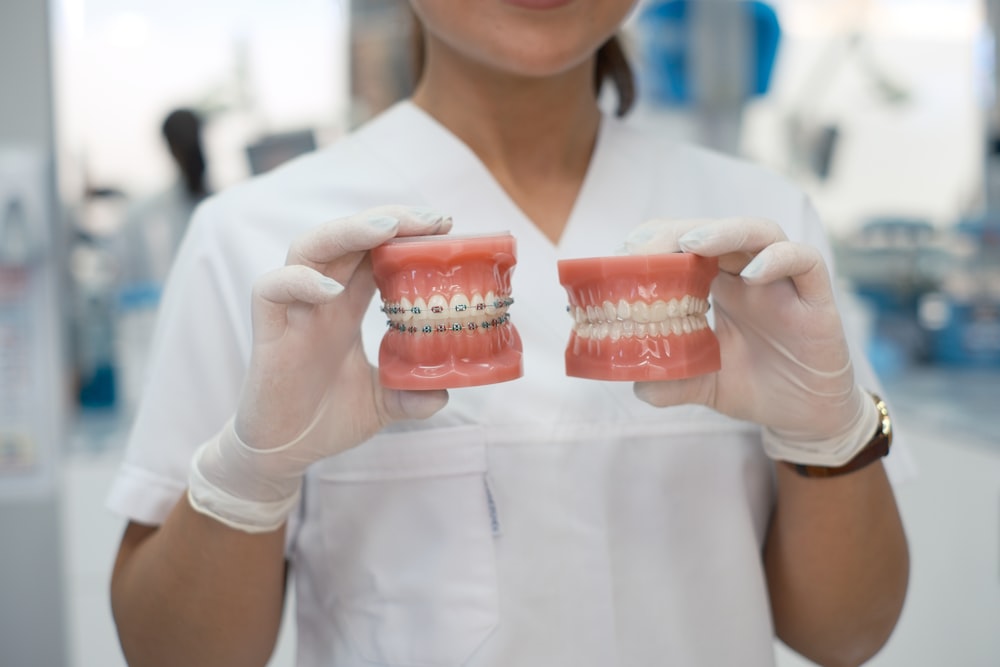 a woman in a dentist's uniform holding a model of a tooth