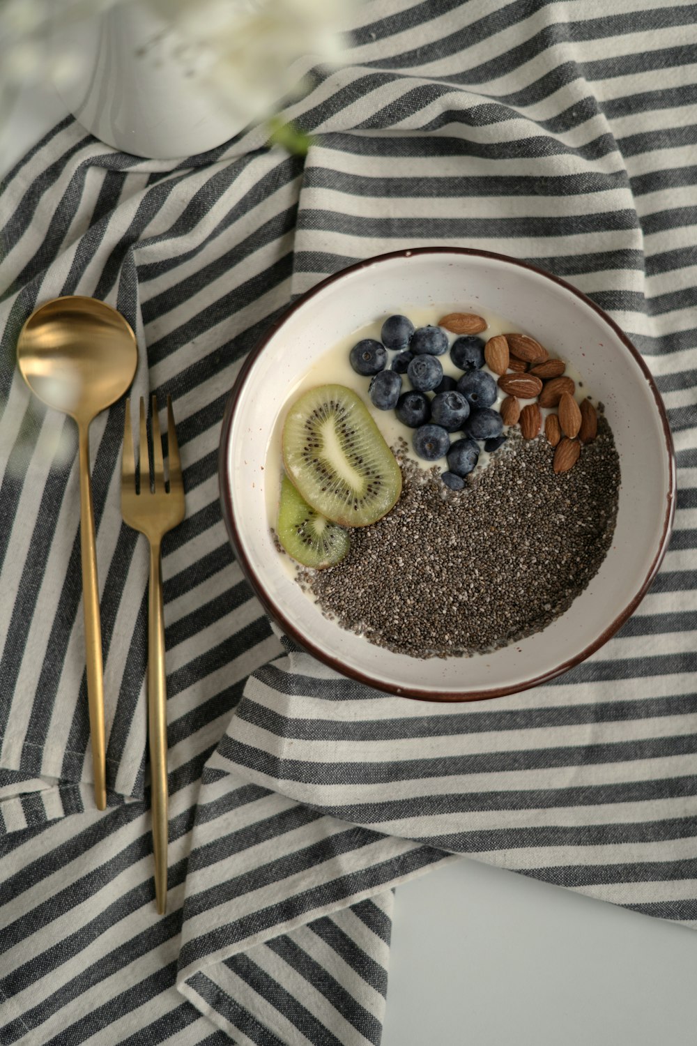 a bowl of cereal with kiwis, bananas, and blueberries