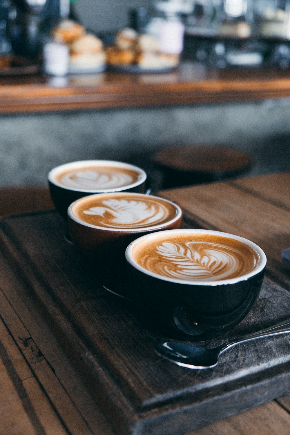 three cups of coffee sitting on top of a wooden table