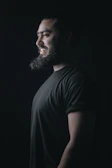 Profile of a confident man with a well-groomed beard under soft lighting.