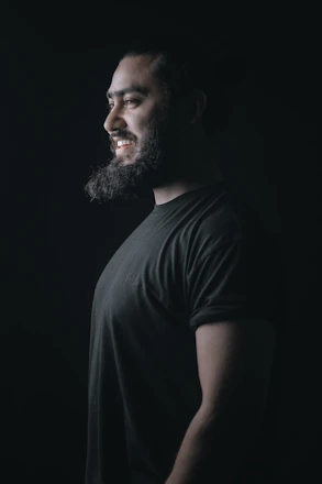 Close-up of a confident bearded man adjusting his grooming routine in natural light.