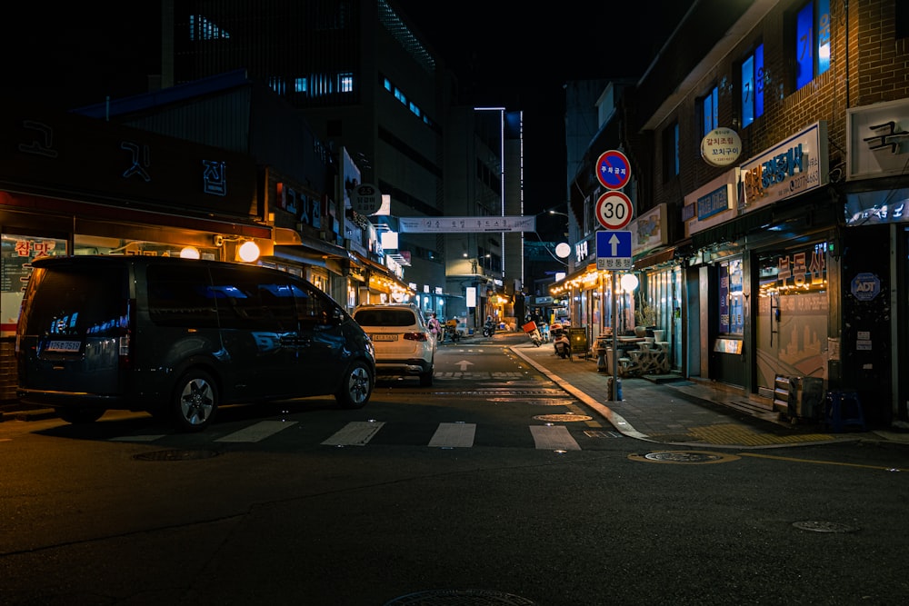 Una calle de la ciudad por la noche con coches aparcados al lado de la calle