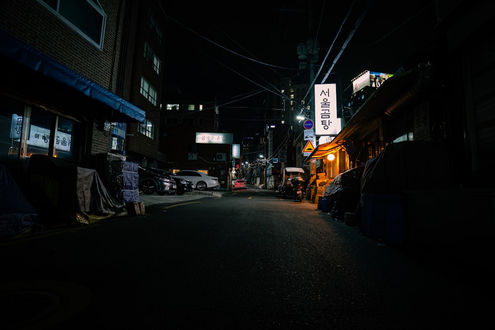 a dark street at night with cars parked on the side of the road