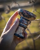 Hand holding a beautifully crafted glass piteira against a blurred background.