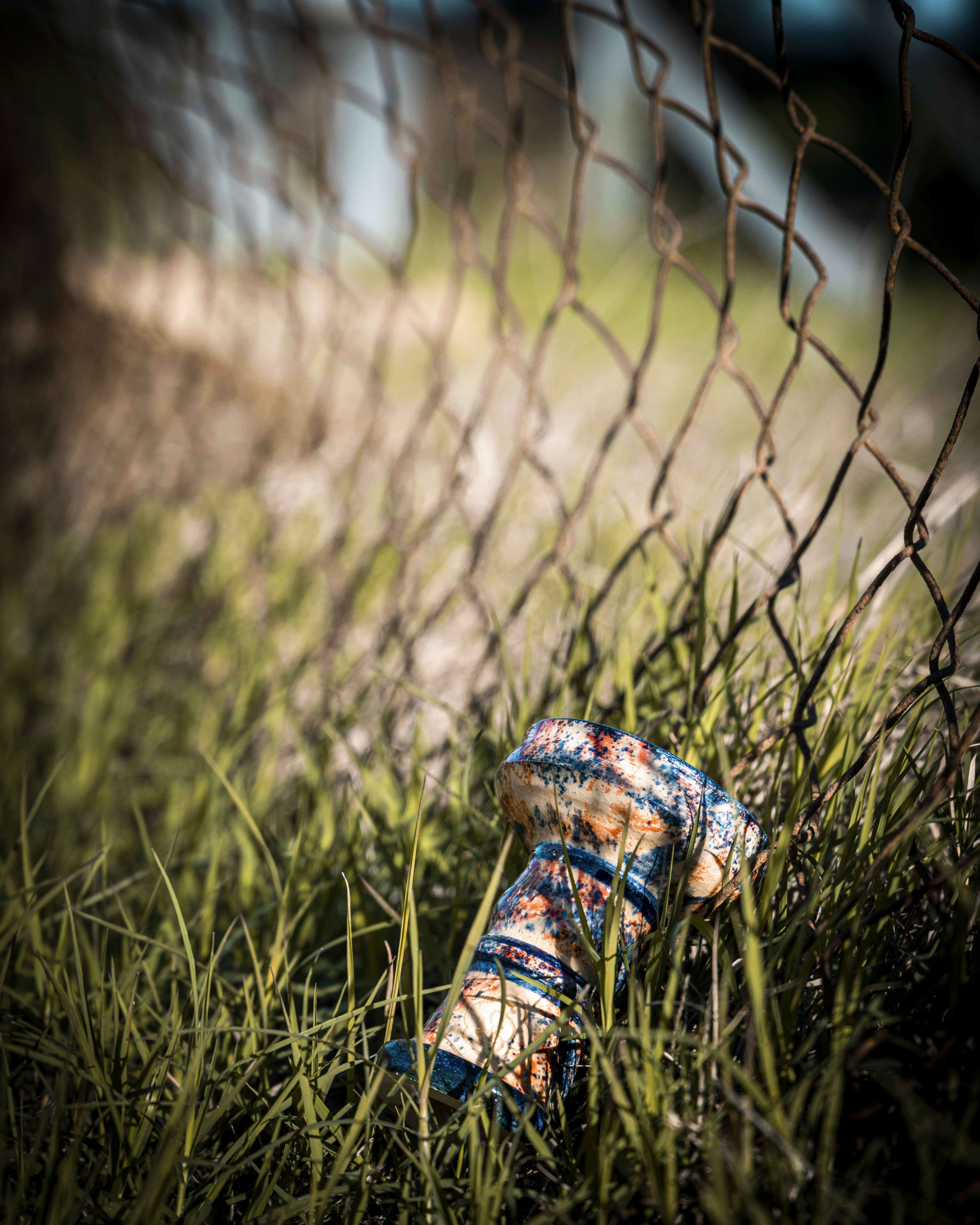 a broken baseball glove sitting in the grass behind a fence