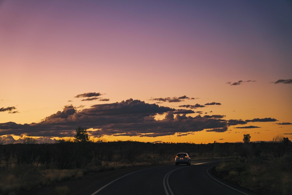 a car driving down a road at sunset