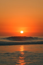the sun is setting over the ocean with waves