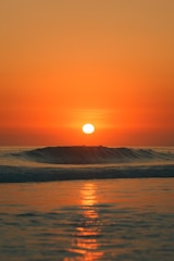 the sun is setting over the ocean with waves