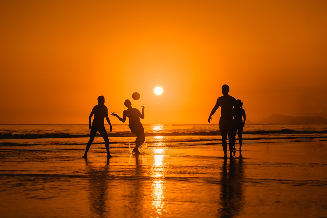 a group of people playing volleyball on the beach