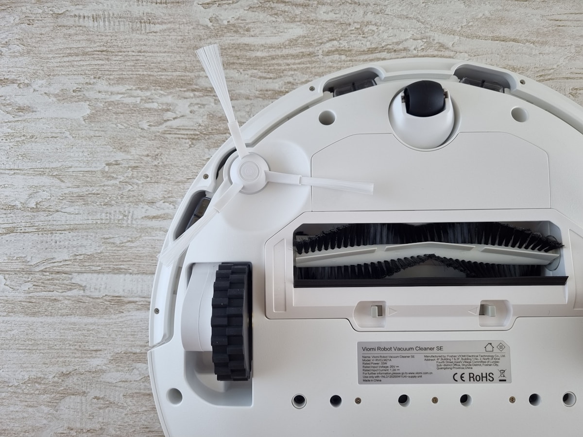 A white robot vacuum sitting on top of a wooden floor