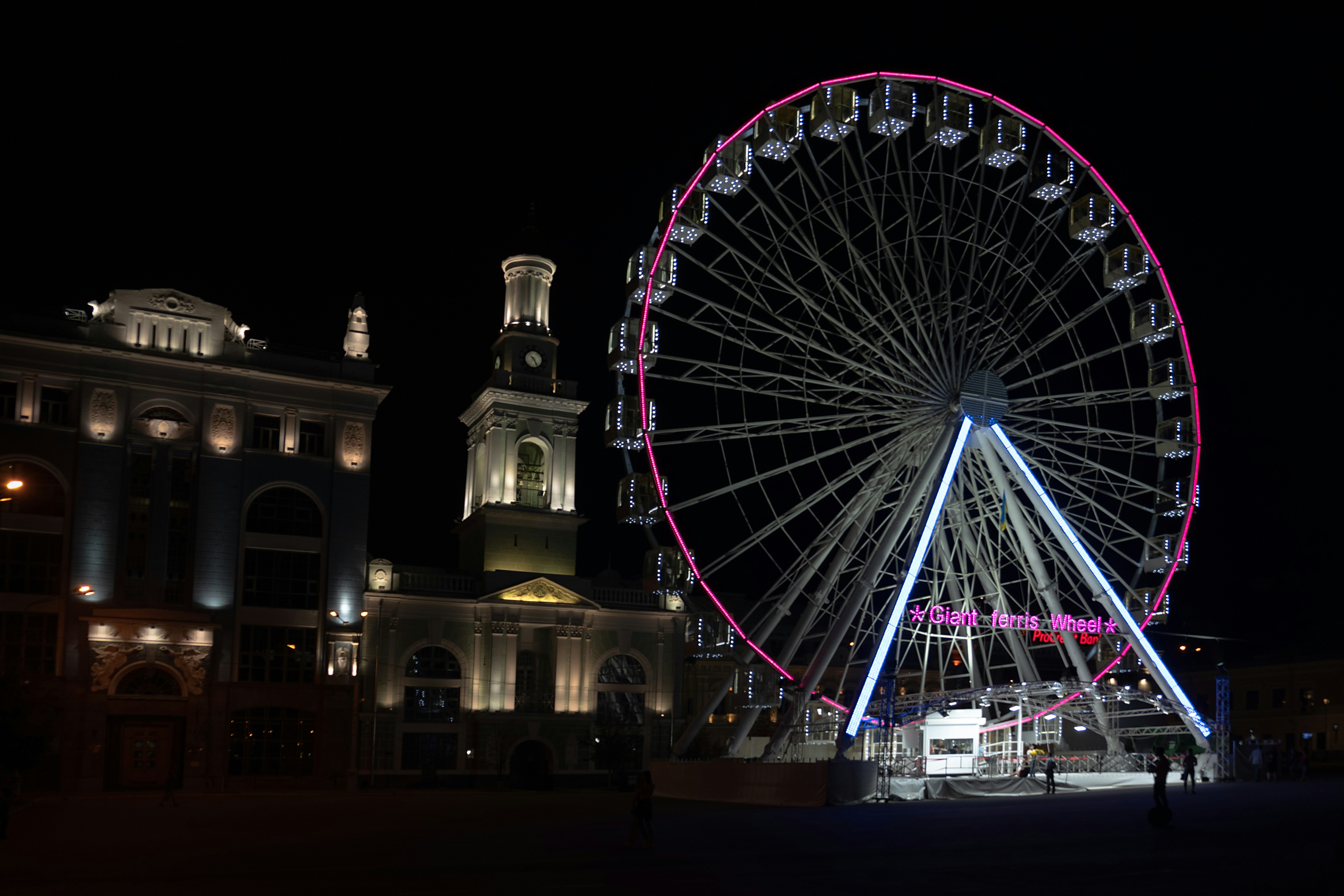 a ferris wheel lit up at night in front of a building