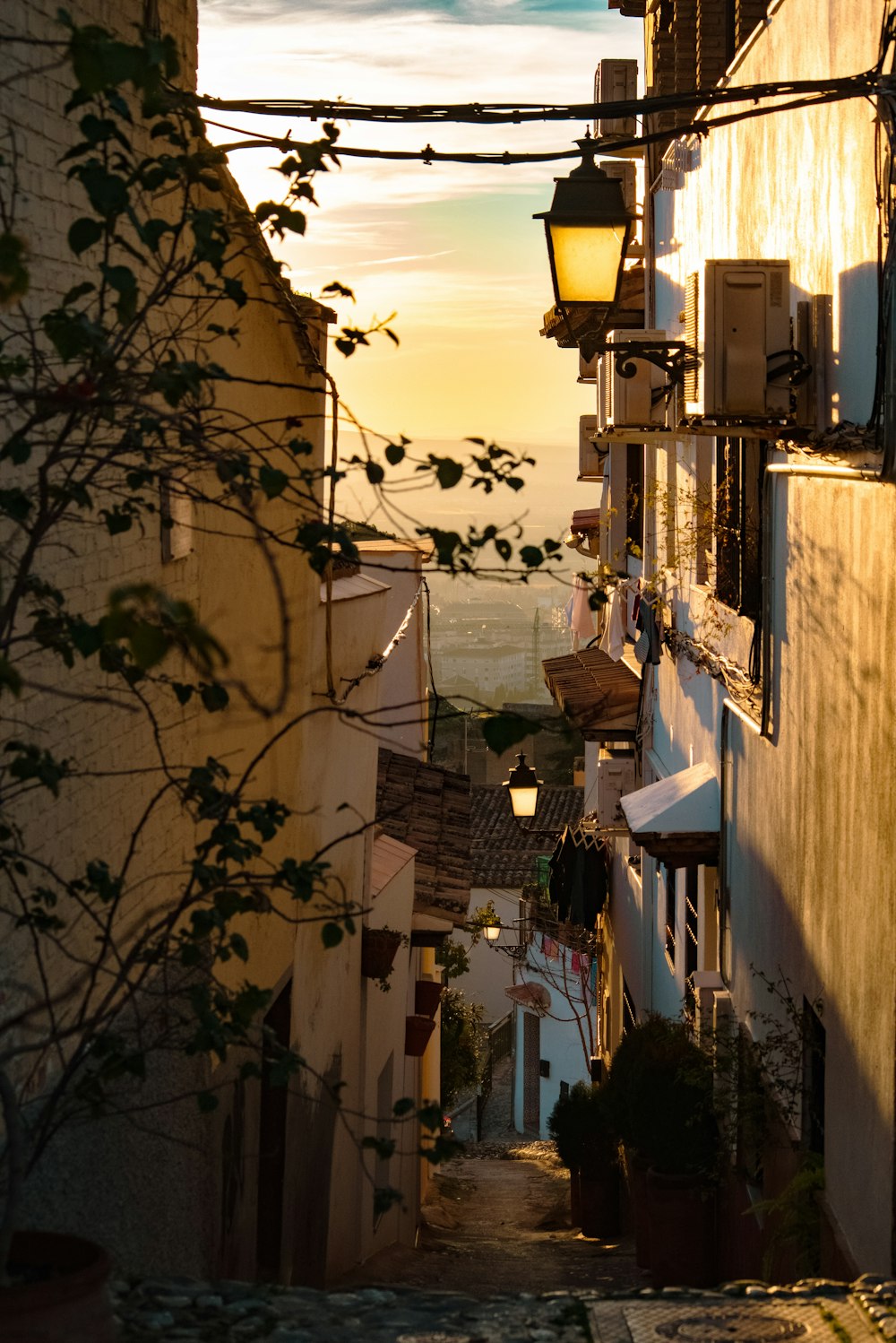 a narrow alley way with a street lamp and a view of the ocean