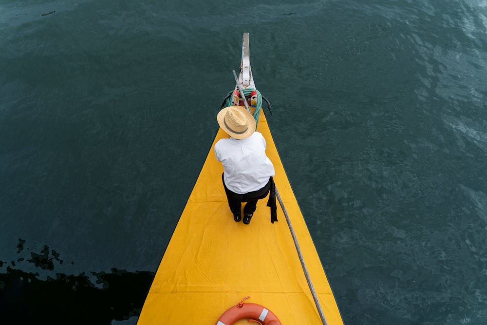 a man sitting on a yellow boat in the water