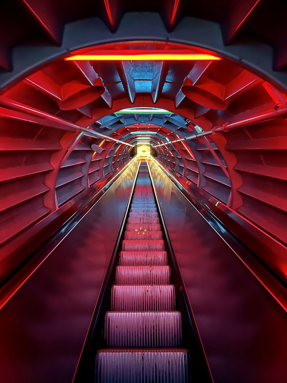 un tunnel rouge et bleu avec un long escalier